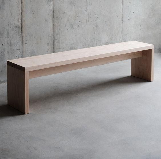 Minimal pale wooden bench against a concrete wall