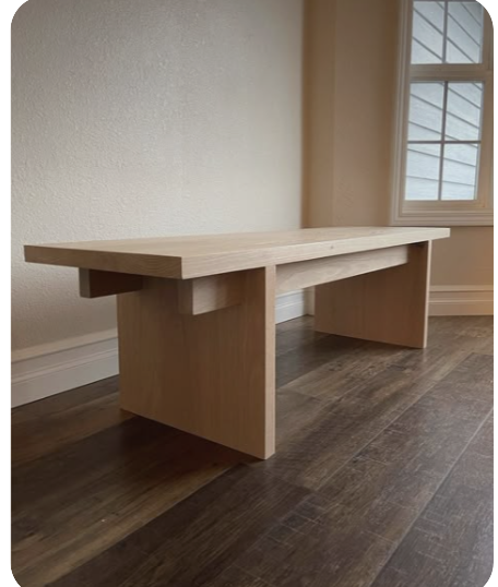 Light wooden table with broad panel legs beside a window